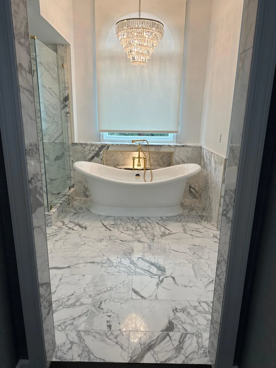 Luxury marble bathroom remodel with freestanding tub and crystal chandelier